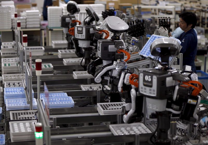 在Glory公司的车间里，一些人形机器人和人类员工一起工作。